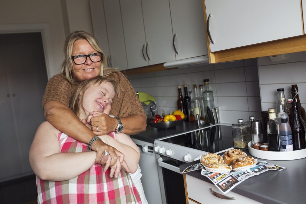 Mother hugging daughter with down syndrome in kitchen